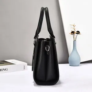 Side view of black lychee grain leather tote bag with silver D-rings and sturdy handles