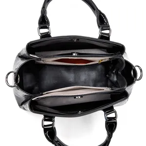 Interior view of black glossy handbag showing spacious main compartment and zip pockets