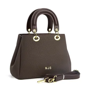 Sac fourre-tout en cuir marron foncé avec logo NJS doré et bandoulière amovible sur blanc