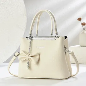 Borsa a mano minimalista beige in similpelle a grana con ciondolo a fiocco e catena d'argento