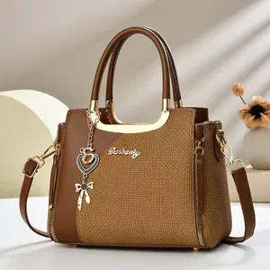Detail der Handtasche aus Leder mit Webstruktur, Goldlogo und dekorativem Anhänger