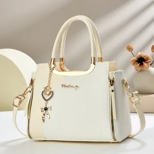 Detail der cremefarbenen Handtasche mit Lychee-Textur und goldenem Schmetterling