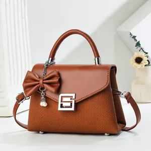 Caramel leather crossbody handbag with bow pendant and elegant silver geometric buckle