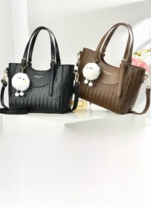 Détail de sacs cabas tissés noir et marron avec breloque peluche et bandoulière