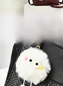 Gros plan d'un bijou de sac en fausse fourrure blanche avec des yeux de dessin animé