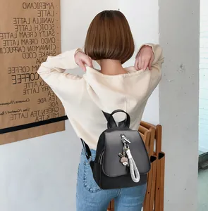 Close-up of black leather backpack with rabbit charm and side stripe texture detail
