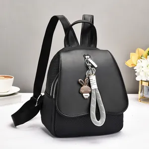 Fashionable black casual backpack with bunny charm and decorative strap on a desk