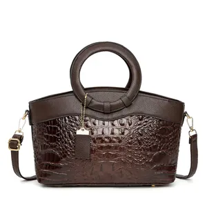 Detail of dark brown handbag showing crocodile texture and round gold handle detail