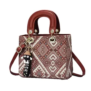 Red and white geometric woven handbag with red leather trim and a cute cartoon charm