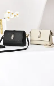 Detail view of lychee texture flap crossbody bags in black and beige with gold buckles