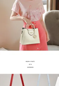Detail of cream white leather handbag with golden chain handle and camellia charm
