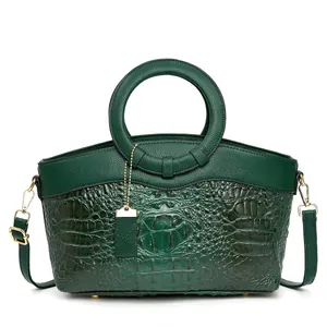 Detail of dark green crocodile pattern leather tote with gold hardware and round handle