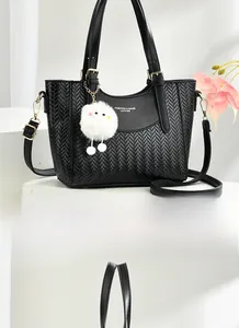 Détail d'un sac cabas noir tissé avec pendentif en peluche et bandoulière métallique