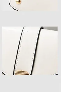 Gros plan des clous de fond dorés et des coutures fines sur le sac à main en cuir blanc