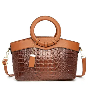 Detail of two-tone brown tote bag with crocodile texture and circular handle
