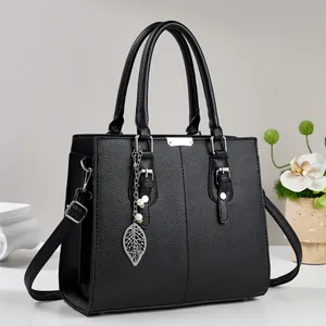 Détail d'un sac à main en cuir grainé noir avec pendentif feuille et perle élégant