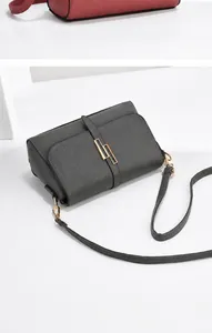 Close-up of pebble leather texture and gold geometric buckle on a crossbody shoulder bag