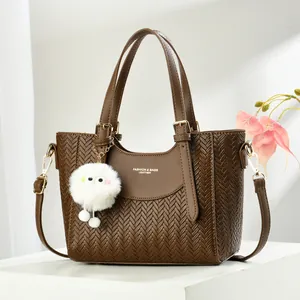 Sac à main marron foncé à texture tissée avec détails dorés et pompon blanc en peluche