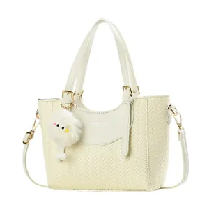 Sac à main beige texturé à chevrons avec détails dorés et breloque peluche sur fond blanc