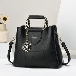 Black faux leather tote bag with geometric stitching, rose pendant and chain straps