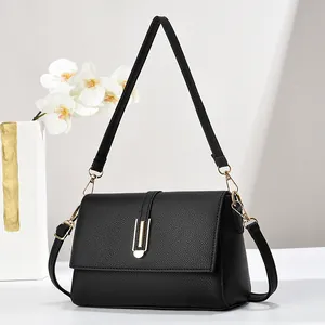 Detail of black lychee grain leather handbag with gold rectangular buckle and dual straps