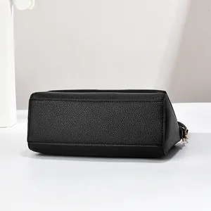 Detail view of the flat bottom and textured black litchi pattern leather on the shoulder bag