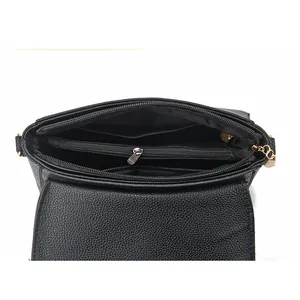 Detail view of the black crossbody bag's interior showing a zippered compartment and lining