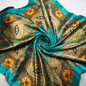 Detailed view of paisley silk scarf with glossy teal satin fabric and floral pattern