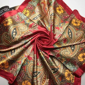 Detail of teal paisley print silk scarf showing satin texture and intricate floral patterns