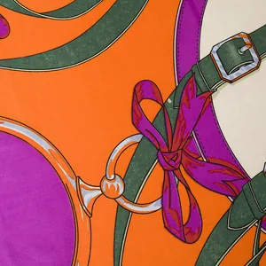 Detailed close-up of silk twill fabric featuring equestrian belts and metal buckle patterns