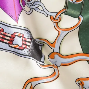 Macro detail of silk scarf showing equestrian chain patterns and smooth satin texture