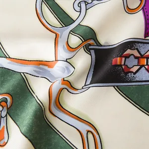 Macro shot of silk twill scarf detail showing green harness straps and silver metal chain