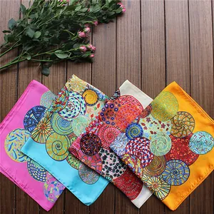 Flat lay of four colorful square scarves with geometric patterns on a dark wood floor