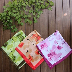 Three elegant square scarves with abstract art prints displayed on a wooden surface