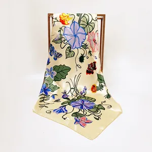 Detail of silk satin scarf featuring blue morning glory and butterfly prints on cream base