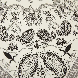 Macro detail of the paisley print and geometric border on a black and white silk satin scarf