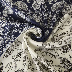 Close-up of paisley pattern satin scarf in navy blue and cream with silky texture