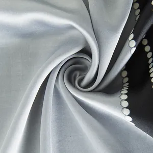 Macro shot of silk scarf showing spiral fold, silver satin sheen and white polka dots