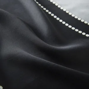 Detail of silk-like satin fabric showing smooth texture and white polka dot edge pattern