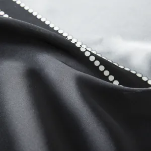Macro view of smooth silk texture with white polka dot pattern on grey fabric