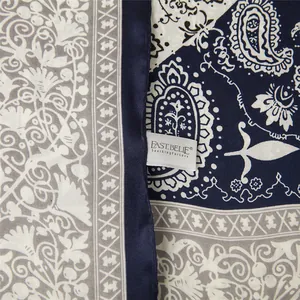 Detail of satin square scarf with paisley floral prints and navy blue border finish