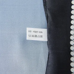 Detail of blue geometric silk-like scarf showing material texture and fabric care label