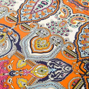 Detailaufnahme des 100cm Seidenschals mit orangefarbenem Paisleymuster und feiner Stoffstruktur