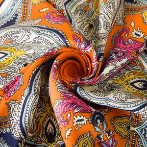 Makroaufnahme des farbenfrohen Paisley-Musters auf einem Seidenschal mit Orangetönen