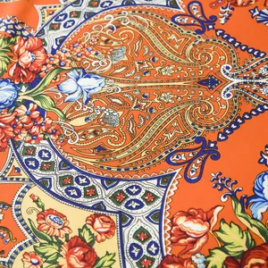 Detailed macro view of vibrant orange bohemian silk scarf with paisley floral pattern