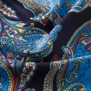 Close-up of paisley floral pattern on blue silk scarf with soft fabric folds