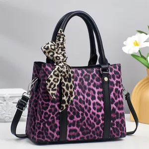 Detail of purple leopard print handbag featuring silk scarf and black lychee texture handles