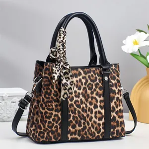Detail of leopard print handbag with silk scarf wrapped handle and silver hardware