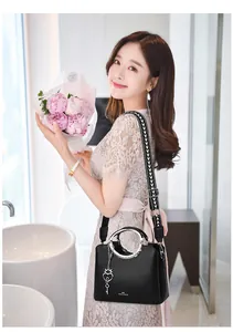 Detail of black lychee grain leather tote bag with silver ring handle and heart pendant