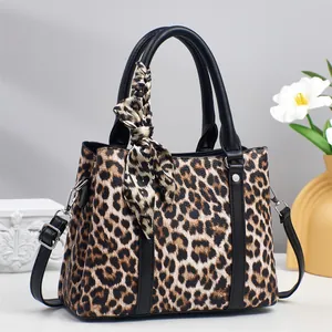 Detail view of leopard print handbag with silk scarf and detachable shoulder strap
